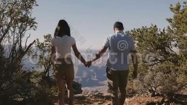 后景<strong>年</strong>轻的成<strong>年</strong>浪漫夫妇<strong>携手</strong>漫步到美国亚利桑那州大峡谷的史诗般全景。